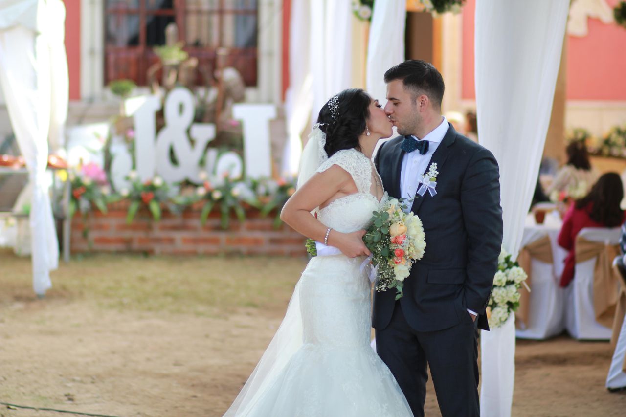 Bride and groom share a romantic kiss at their outdoor wedding ceremony.